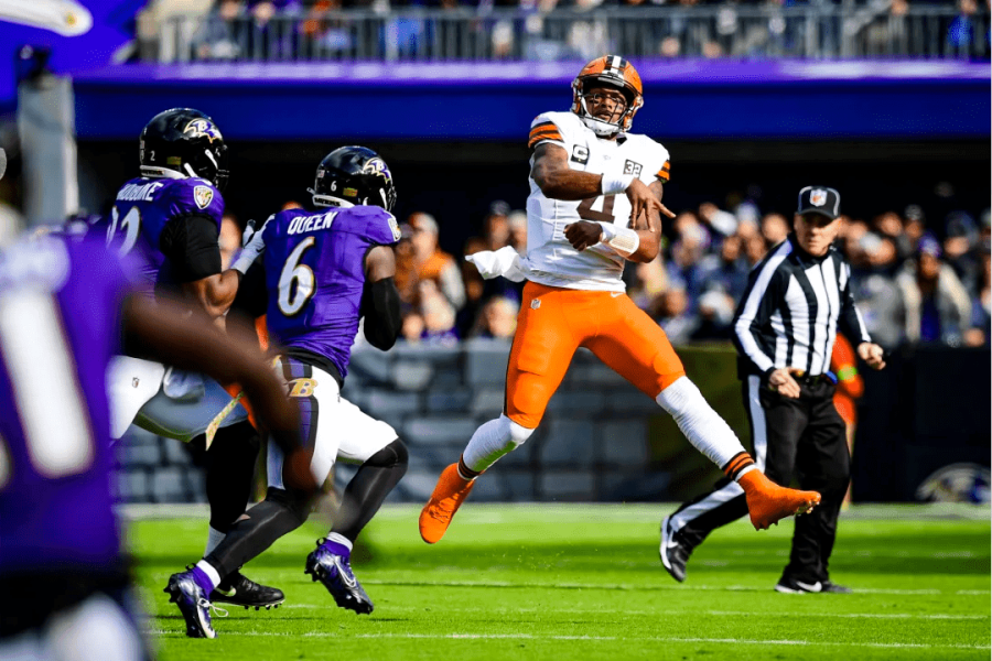 Três jogadores de roxo do Baltimore Ravens cercando o quarterback do Cleveland Browns de branco