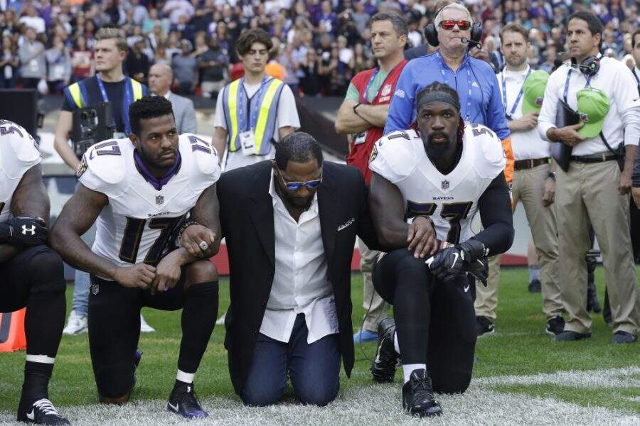 Baltimore Ravens wide receiver Mike Wallace, from left, former player Ray Lewis and inside linebacker C.J. Mosley lock arms and kneel down during the playing of the U.S. national anthem before an NFL football game against the Jacksonville Jaguars at Wembley Stadium in London, Sunday Sept. 24, 2017. (AP Photo/Matt Dunham) ORG XMIT: TH112