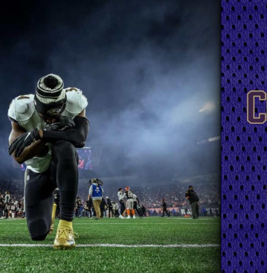 Homem de camisa branca ajoelhado em um gramado de estádio de futebol americano com o céu noturno, após derrota em partida de playoffs