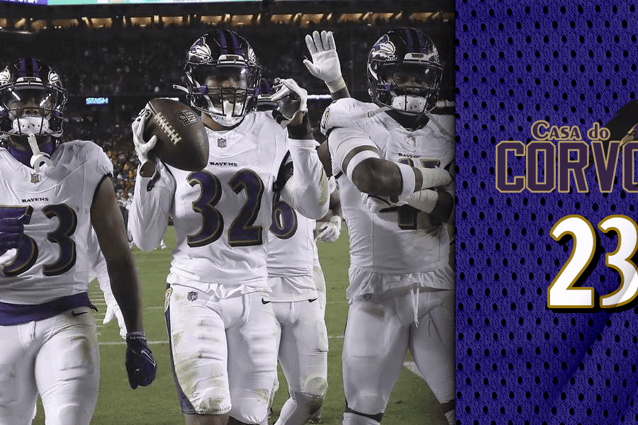 Três jogadores de futbol americano trajando capacete preto, camisa e calças brancas com os adereços do Baltimore Ravens, com o jogador do meio segurando uma bola